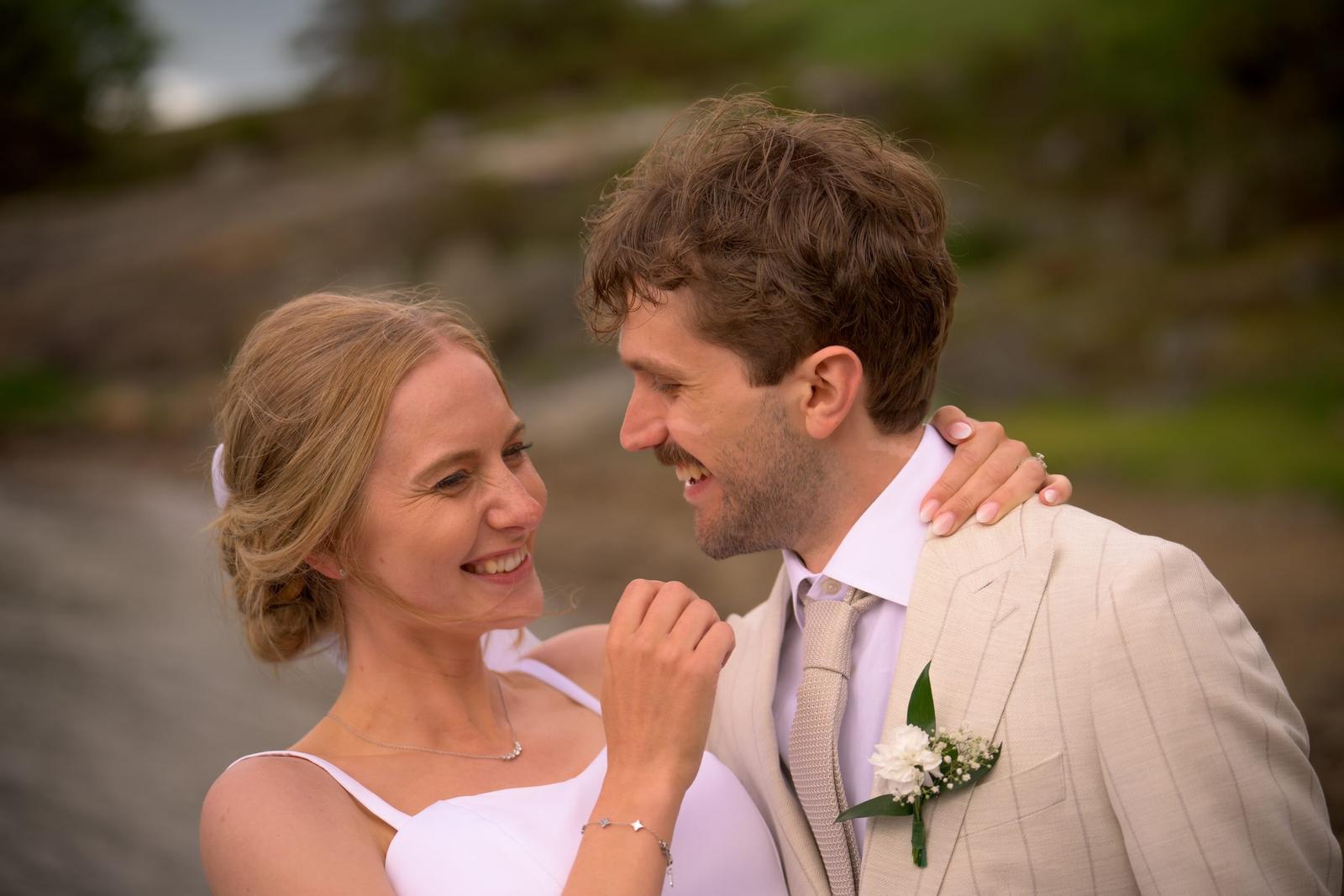 Bride and groom laughing together in a close-up portrait by the water, wedding photography at Villa Vanahem