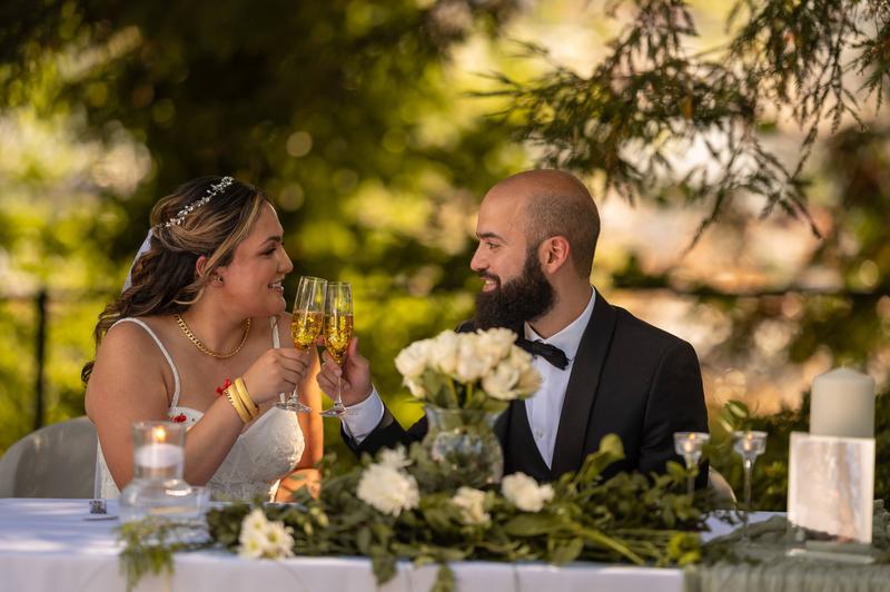 Bride and groom toasting with champagne at a table set with white flowers