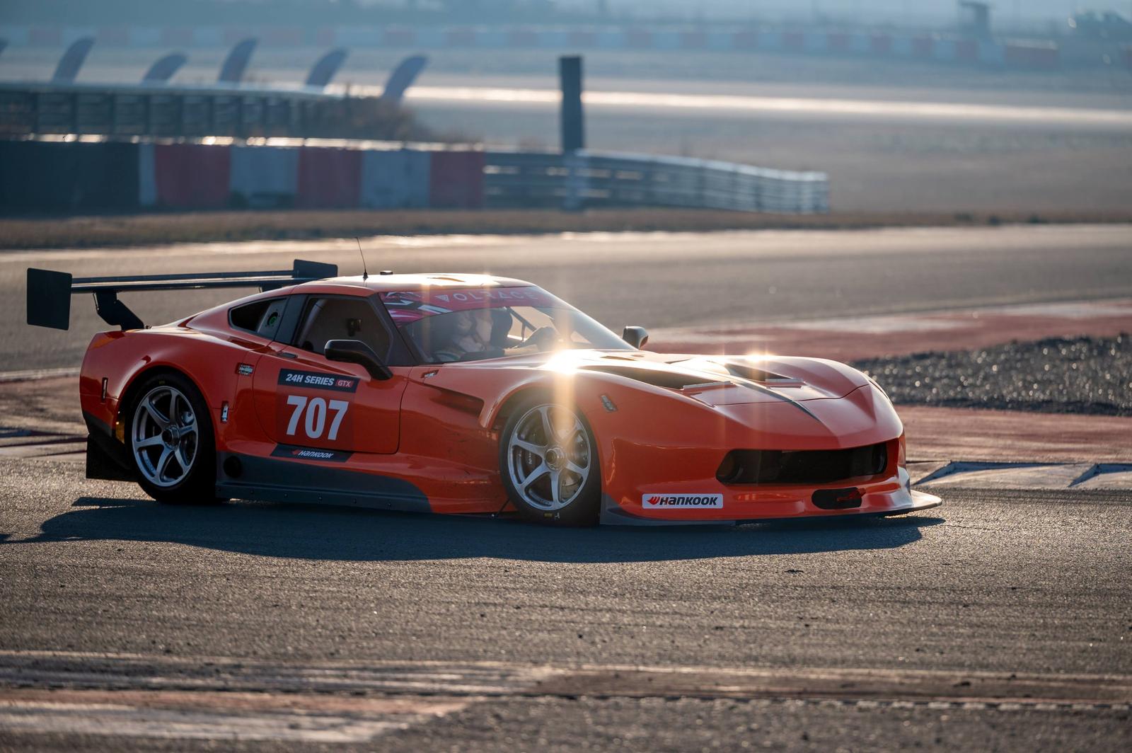 Sport: a red race car with number 707 on a race track, backlit by the sun